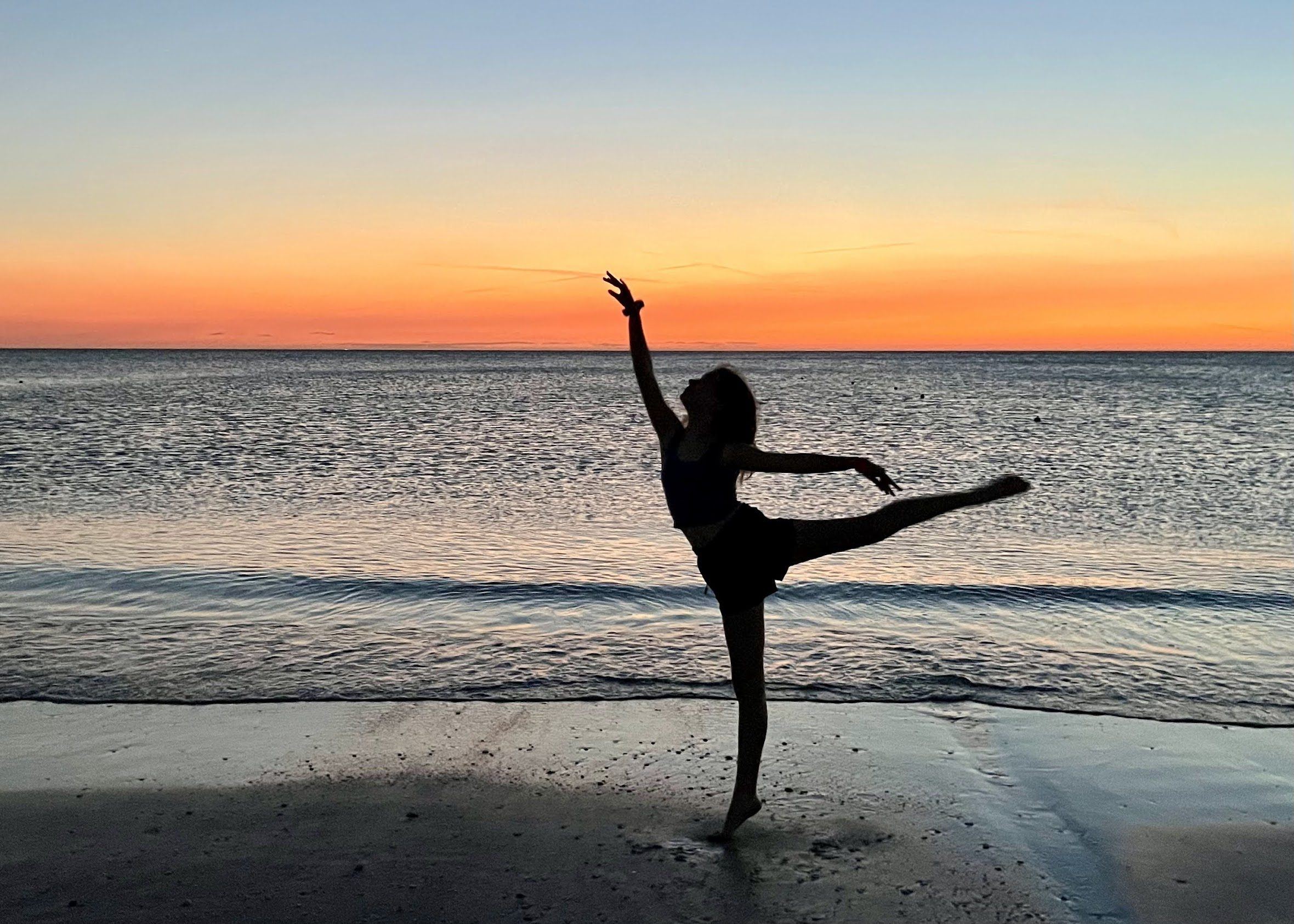 A Fresh Coast Dance dancer in extension at sunset on the Lake Michigan shore