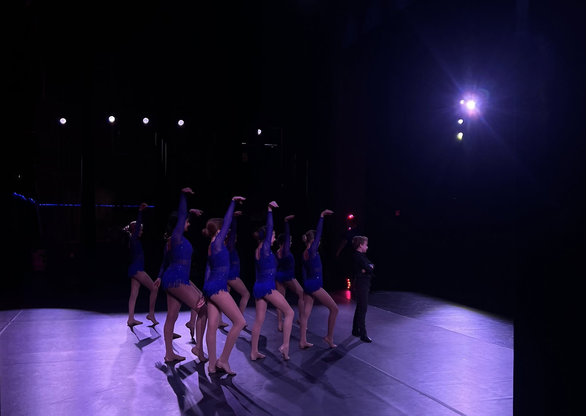 Dancers performing together under purple stage lights